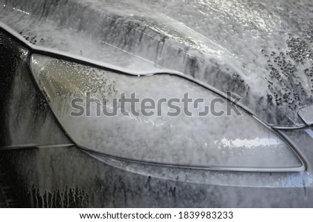 Car body is covered with soap foam to remove dirt from the body