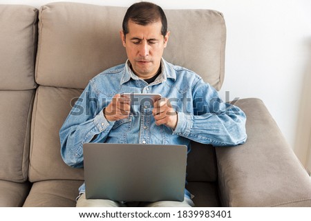 Cropped shot of a young man bet online on the phone on his couch at home office
