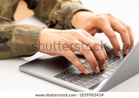 Closeup shot of a unrecognizable military person typing on a laptop keyboard