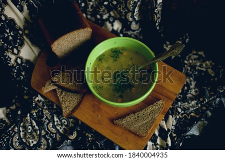 
a regular lunch that includes soup with herbs three slices of bread on a dark background