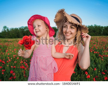 Young girl with her daughter in a poppy field