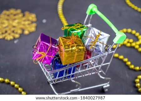 Shopping cart full of minimal present boxes. Gifts for Christmas or New Year with holiday decoration. Black background
