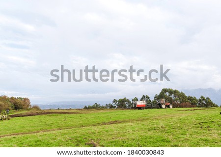 red agricultural tractor standing in a meadow on top of a hill. rural and environment concept