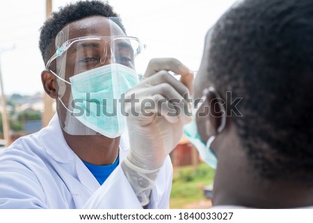 an african lab scientist taking nasal sample from a man Royalty-Free Stock Photo #1840033027