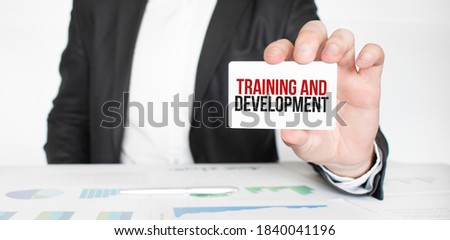 businessman holding a card with text TRAINING AND DEVELOPMENT