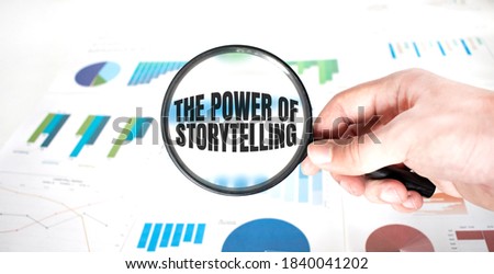 Magnifying glass with words THE POWER OF STORYTELLING over wooden background. Business concept.