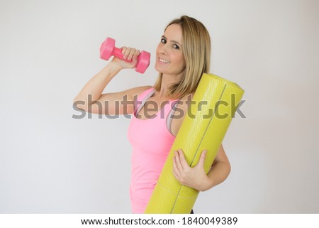 Beautiful woman holding yoga mat in hand over white background.