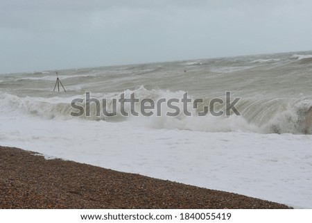 A photo of waves and pebble beach at stormy sea on a rainy day