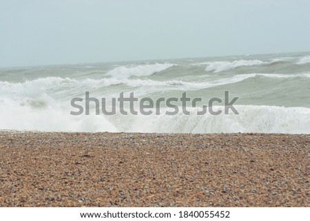 A beautiful photo of waves and pebble beach at stormy sea on a rainy day