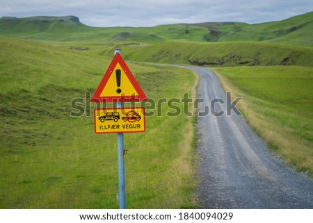 Warning road sign that prohibits the passage of non-off-road vehicles. Only 4x4, all-wheel drive. On the background of the road going to the horizon and mountains covered with green grass in Iceland