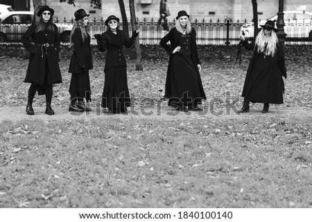 Five women as witches go to the Sabbath, a group of witches or Goths in black clothes and hats go down the street
