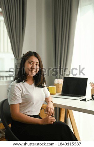 Portrait of female smile and looking into camera while sitting in home office.