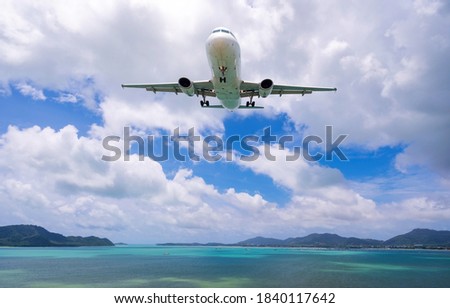 Commercial airplane landing above sea and clear blue sky over beautiful scenery nature background