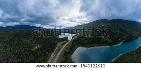 Panoramic View of Lakes from Above surrounded by Forest, alongside Scenic Road at Twilight. Aerial Drone Shot taken in Canadian Nature. Klondike Highway, South of Whithorse, Yukon, Canada.