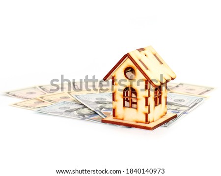 a wooden model of the house stands on a pile of american dollars as a symbol of mortgage investment