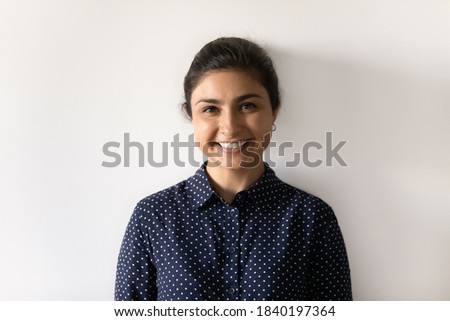 Profile picture of smiling Indian female isolated on grey studio background show optimism and positivity. Headshot portrait of happy young mixed race ethnicity woman renter or tenant feel excited.