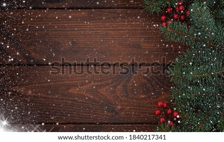 Pine branches with red berries on a wooden background. Christmas snowy background. Happy New Year! Copy space for your text.