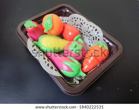 Miniature fruit on a tray made of plasticine with a black table baground