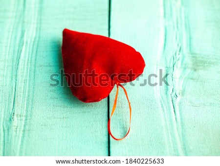 red velvet heart lying on a wooden turquoise surface, red heart on a turquoise background