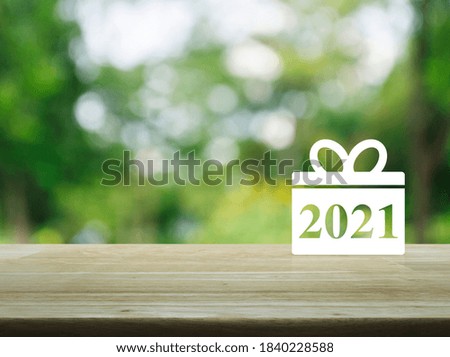 Gift box happy new year 2021 flat icon on wooden table over blur green tree in park, Business shop online concept