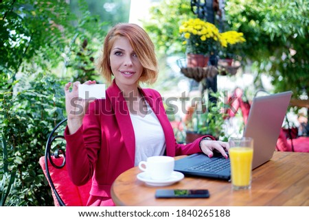 Business lady holding credit card and using laptop in sidewalk cafe 