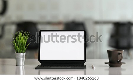 Desktop computer tablet on workspace table showing blank white screen for products or graphic montage.