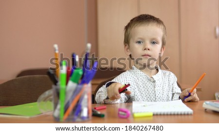 A handsome three-year-old boy sits at the table and counts his fingers on his hand.Preschool education. 4k