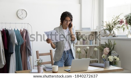 Wide image of young woman stylist talk on cellphone with client or customer, discuss order. Successful Caucasian fashion designer have online smartphone call consultation with consumer at home office.