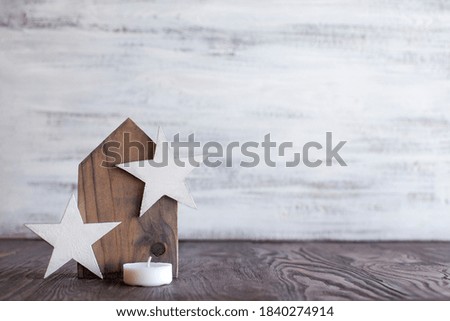 wooden house with wooden stars and a candle on a light wooden background.