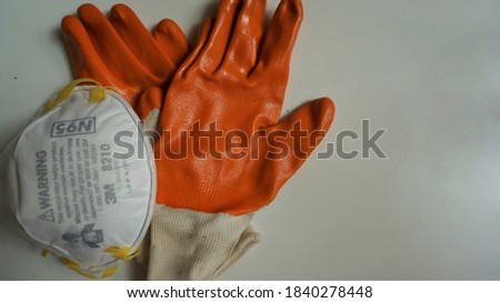 Coronavirus, N95 respirator, FFP2, COVID-19 concept. Medic, and orange gloves sharing protective respirator. Selective focus.