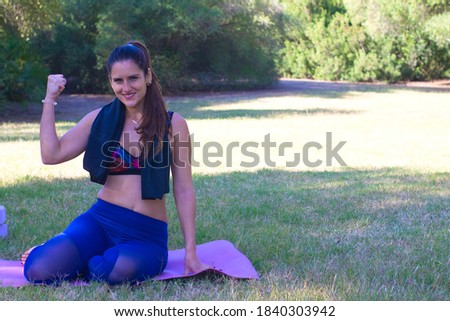 woman sitting in the park on pink mat towel on her neck after a yoga class
