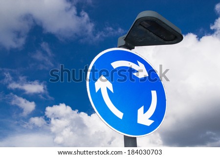 The roundabout street sign with brilliant blue and cloudy skies.