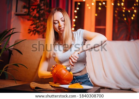 A young girl prepares a pumpkin for halloween. Woman posing with pumpkin and knife. DIY pumpkin lamp. All saints' night at home. Jack lamp at home