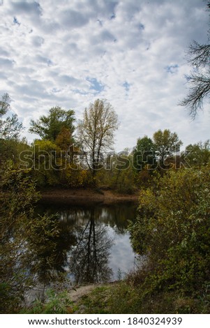 Autumn landscape lake, shore, trees and cloudy sky