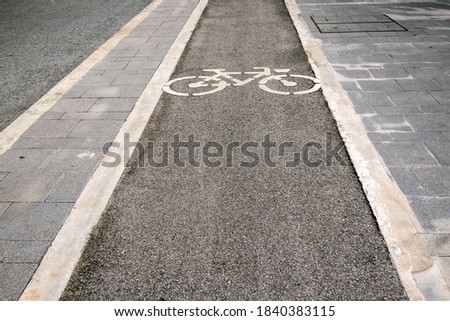 Bicycle lane in the public park, Sign on surface of the asphalt road next to the foot path.