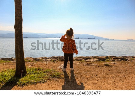 A little girl watches the ships by the beach