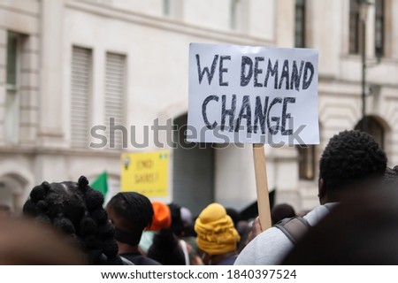 Protester holding a ‘WE DEMAND CHANGE’ placard Royalty-Free Stock Photo #1840397524