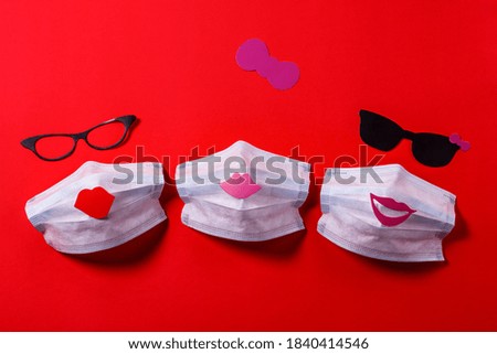 of friendship. medical face mask with glasses and lips of girls made of cardboard on a background of red texture paper.