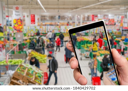 Blurred supermarketon the smartphone screen.. Selling goods in a retail store. Blurred background of shoppers in a store.