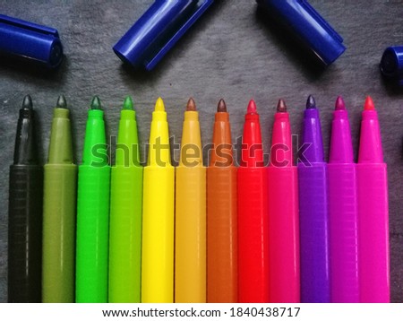 Colored markers for painting on a blackboard background.