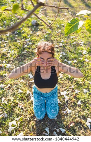 Woman does self-massage of the face, The girl practices yoga on the green grass on a background of green trees, A woman performs asanas at sunset, Meditation in nature, Female fingers on the face.