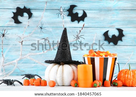 Halloween pumpkins, candies in bucket, candle, spiders and paper bats on blue background