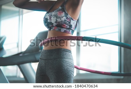 Sporty woman is exercising with Hula hoop in fitness gym for healthy lifestyle concept. Royalty-Free Stock Photo #1840470634