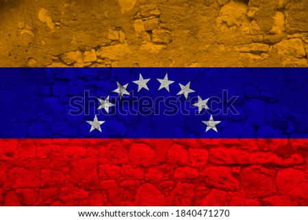 national flag of the state of Venezuela on an old stone wall with cracks, the concept of tourism, emigration, economy, politics, civil rights and freedoms