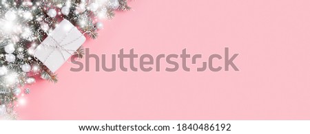 Christmas festive banner of white gift and braches on pink background. Xmas greeting card with space for text. View from above. Flat lay. Happy New year.