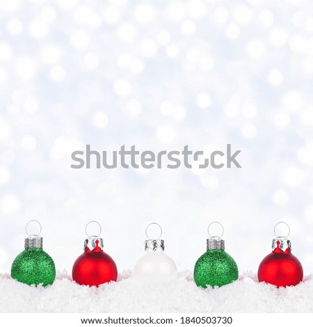 Christmas border of red, white and green ornaments in snow with a twinkling silver light background