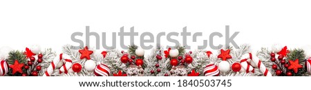 Long Christmas border of red and white ornaments and frosty branches isolated on a white background
