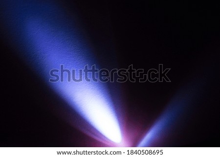Cool blue light from an LED flashlight on a white wall. A ray of light on the surface.