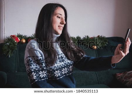 A female taking a selfie on a sofa with Christmas decorations