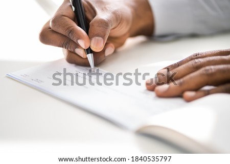 African American Writing Cheque. Signing Paycheck Or Money Check Royalty-Free Stock Photo #1840535797